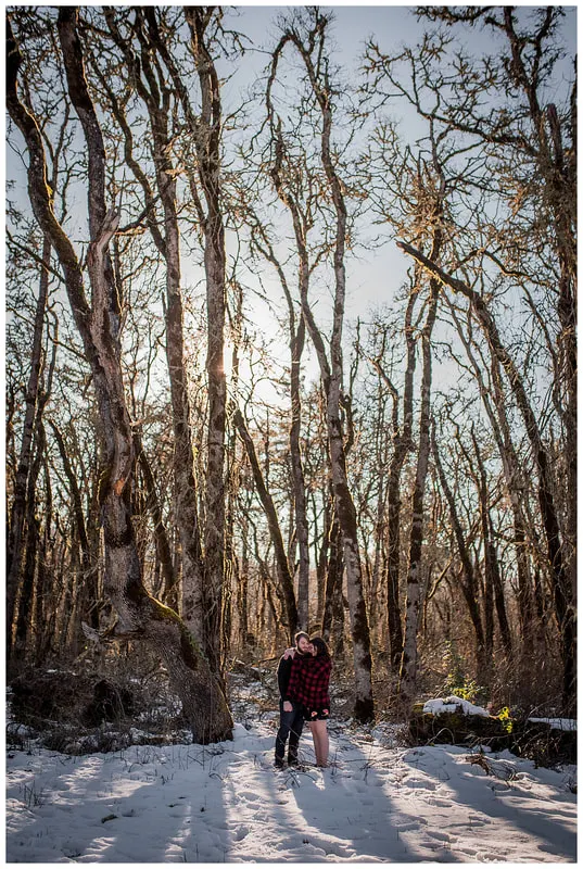 Engagment photo session of a couple taken in trees and snow at Dorris Ranch in Oregon