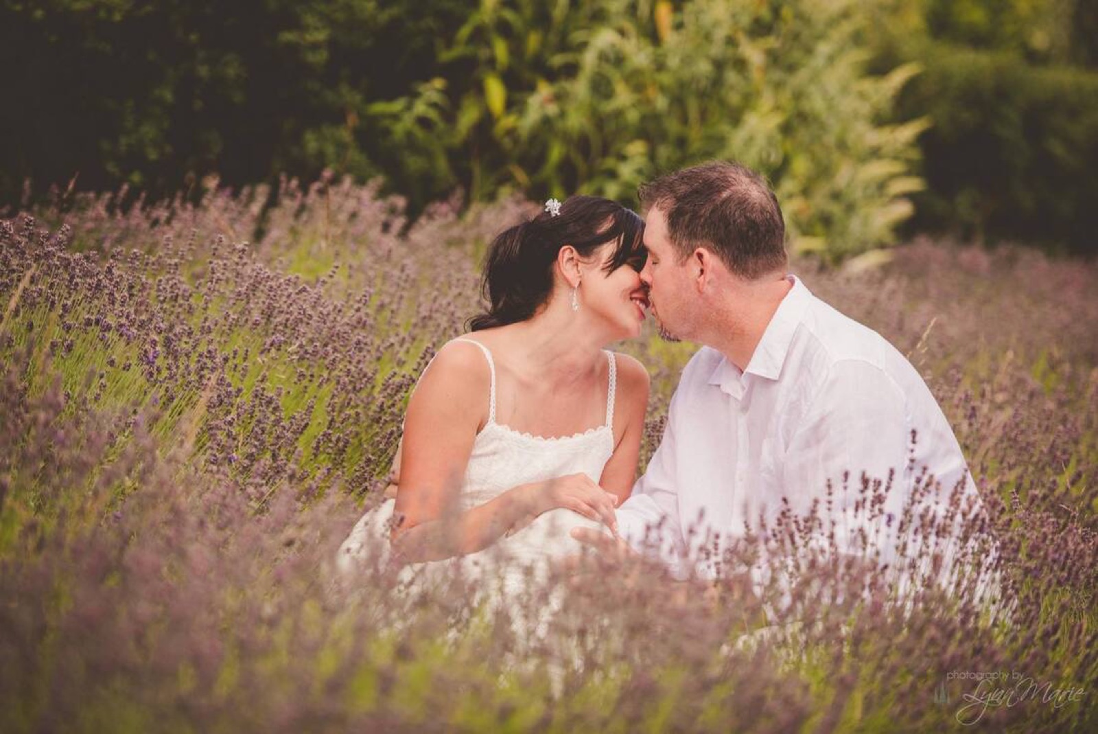 Newlyweds sharing a kiss among purple flowers