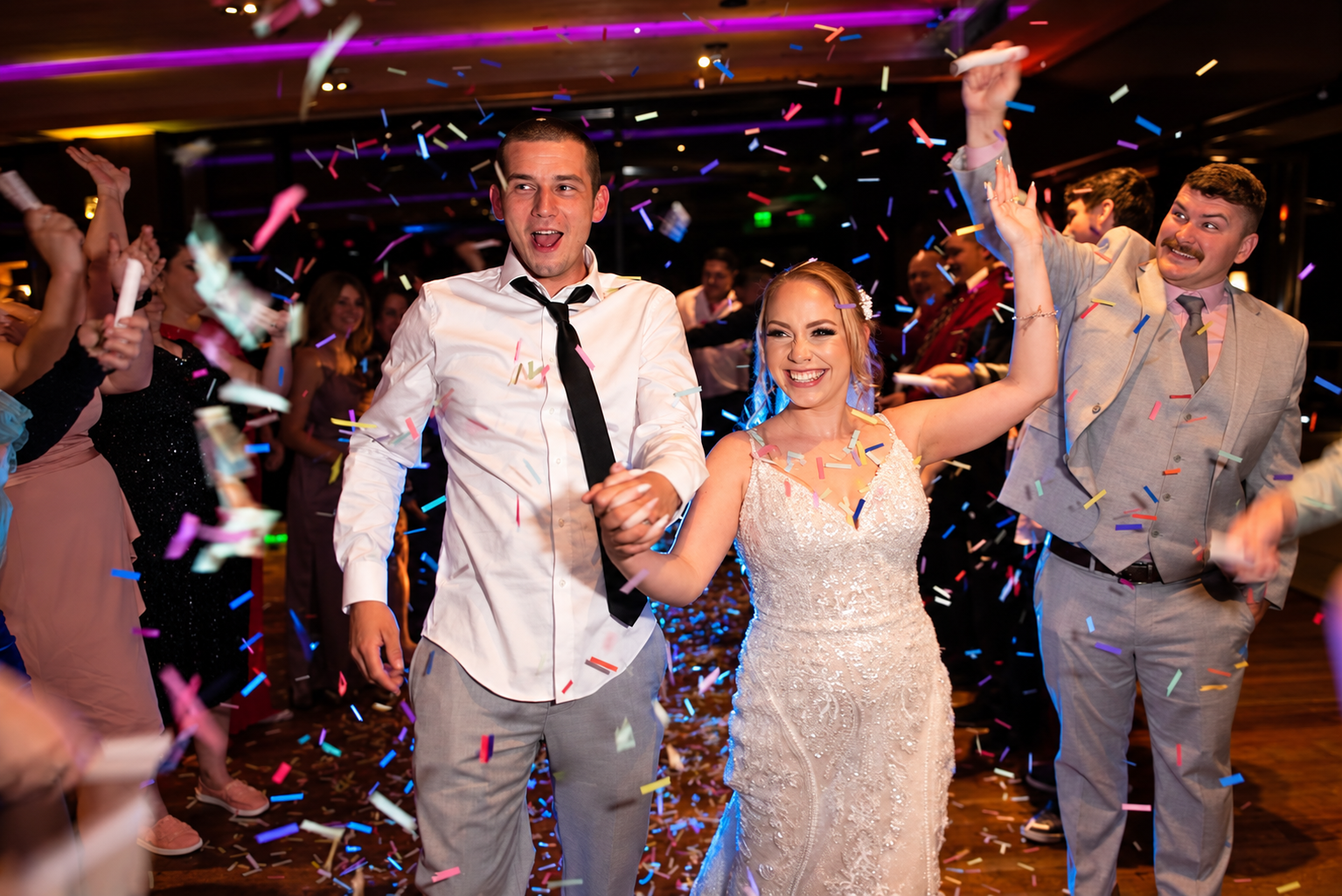 Newlyweds celebrating on the dance floor beneath colorful confetti